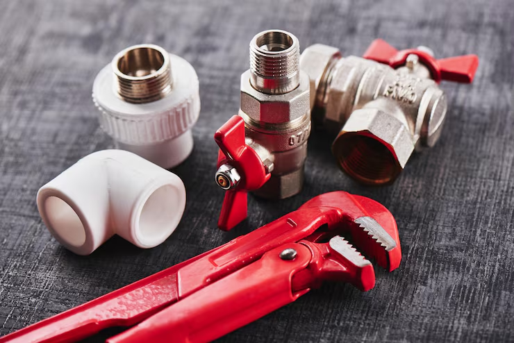 Plumbing fittings and a pipe wrench on a work surface