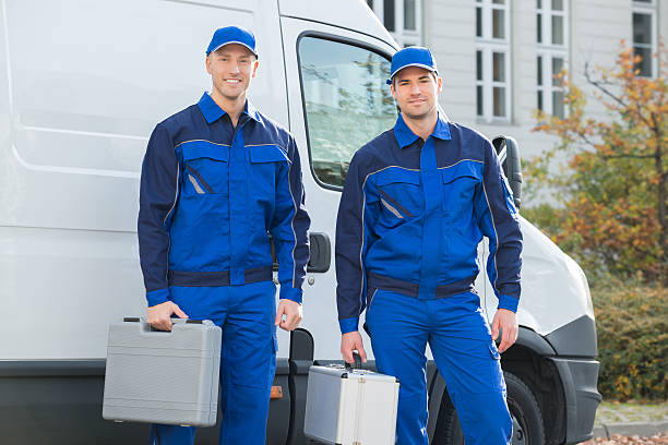 Two uniformed service technicians standing by a work van