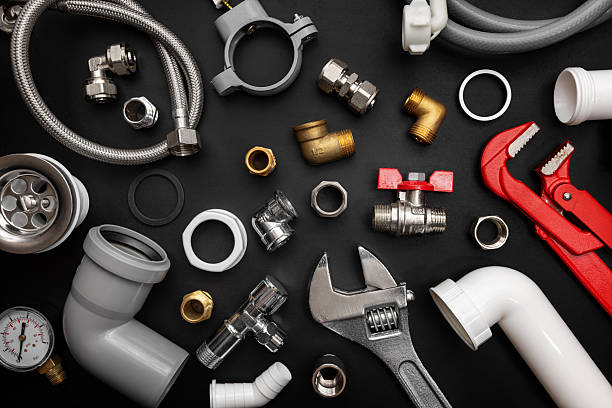 Plumbing tools, pipes and fittings arranged on a workbench
